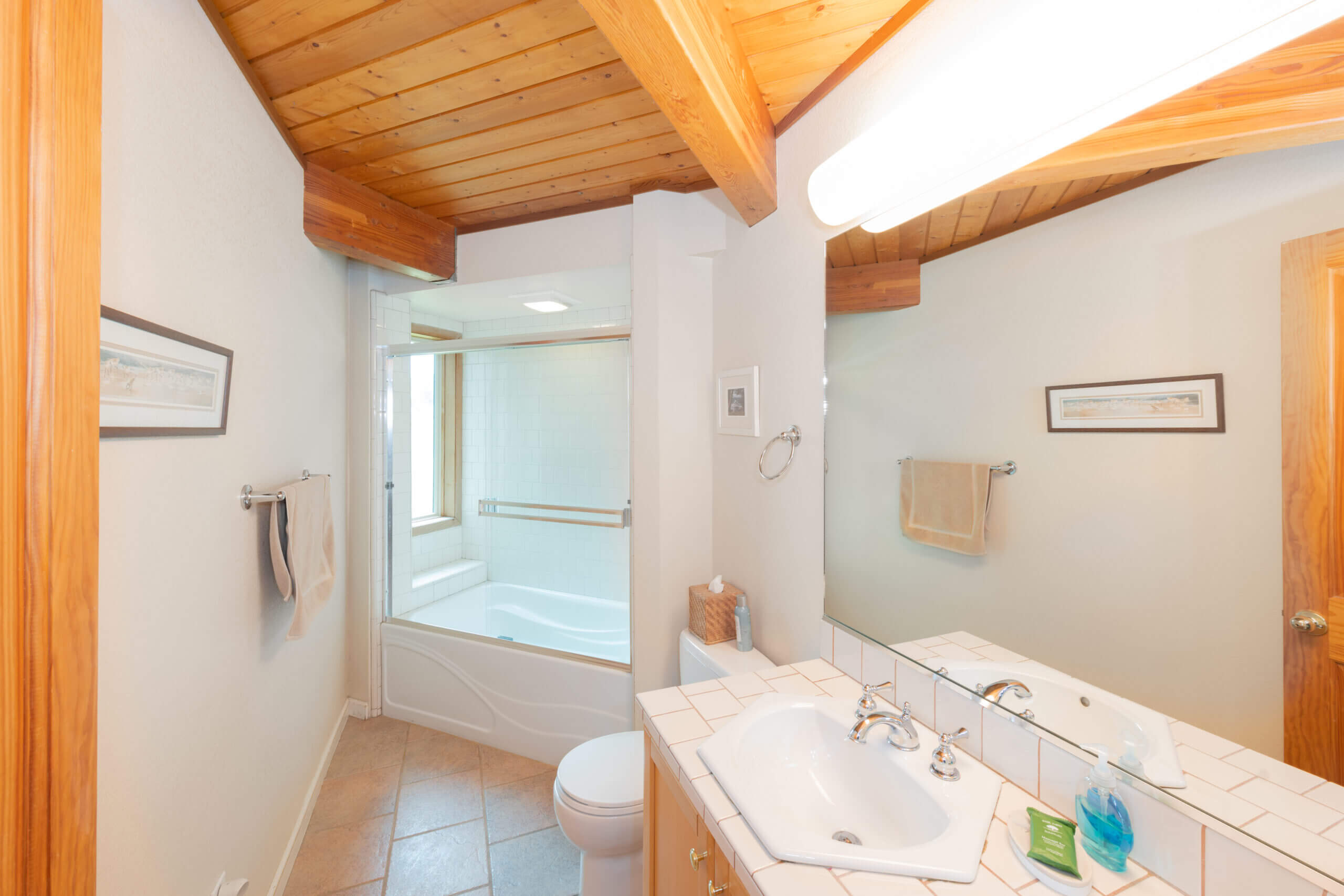 Pelicans Rest downstairs bath with bath shower combo, sink and wood beam ceiling