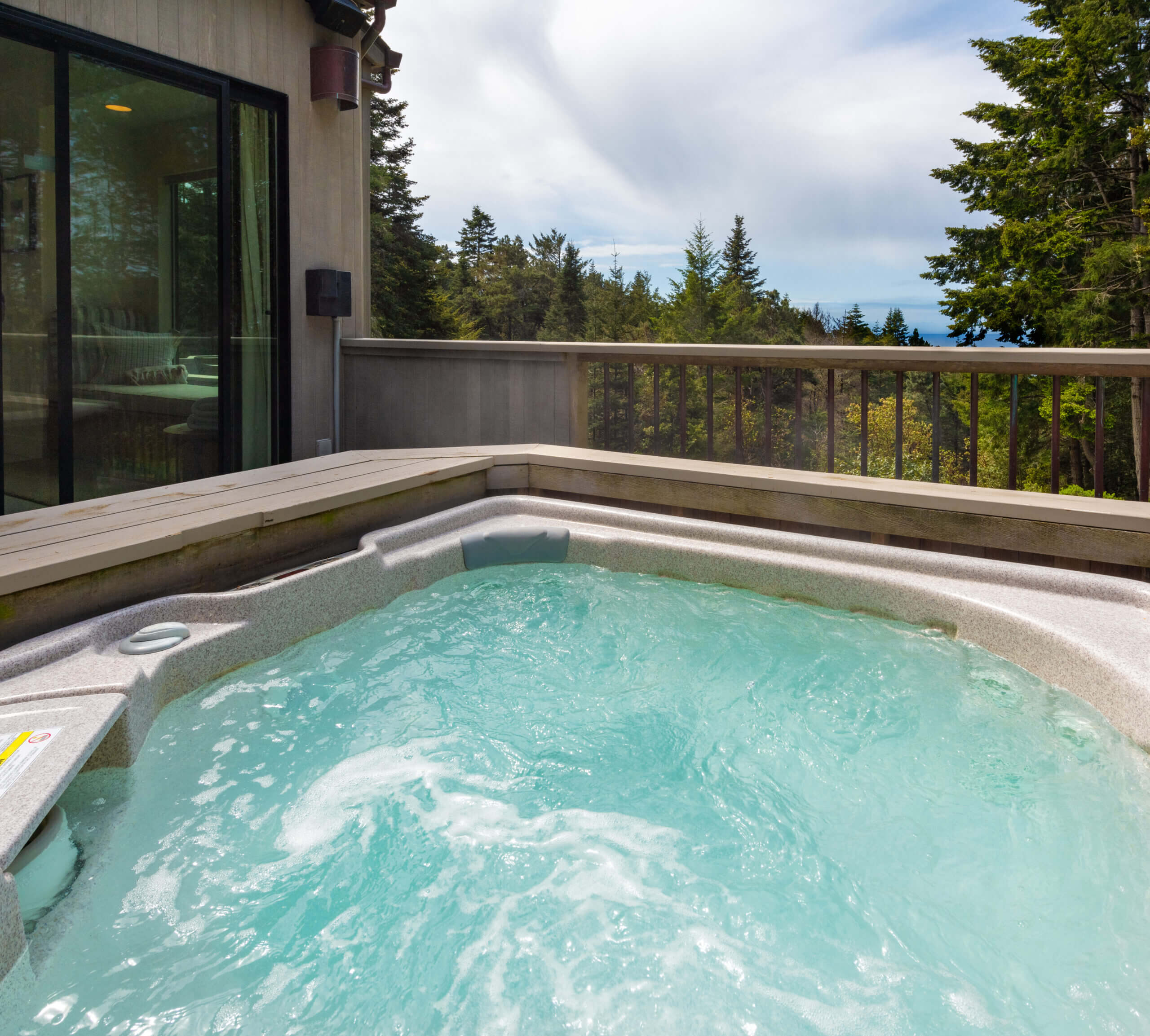Sea Ridge hot tub on deck with view of pine trees and ocean