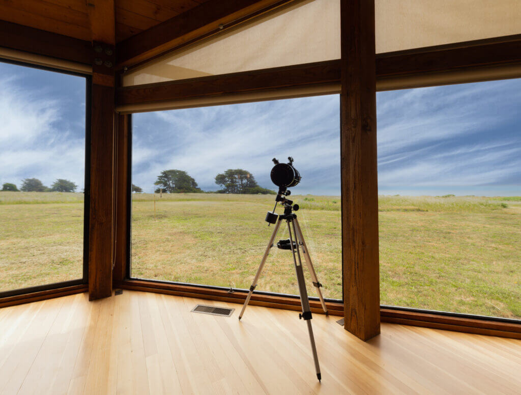 Tin Roof telescope inside looking out window at ocean meadow