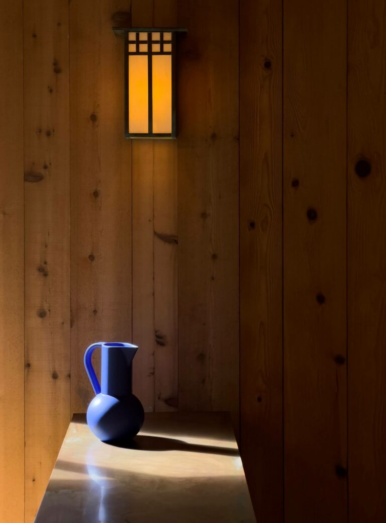 Sea Pony - sunlit wood paneled room with deco blue vase on table.
