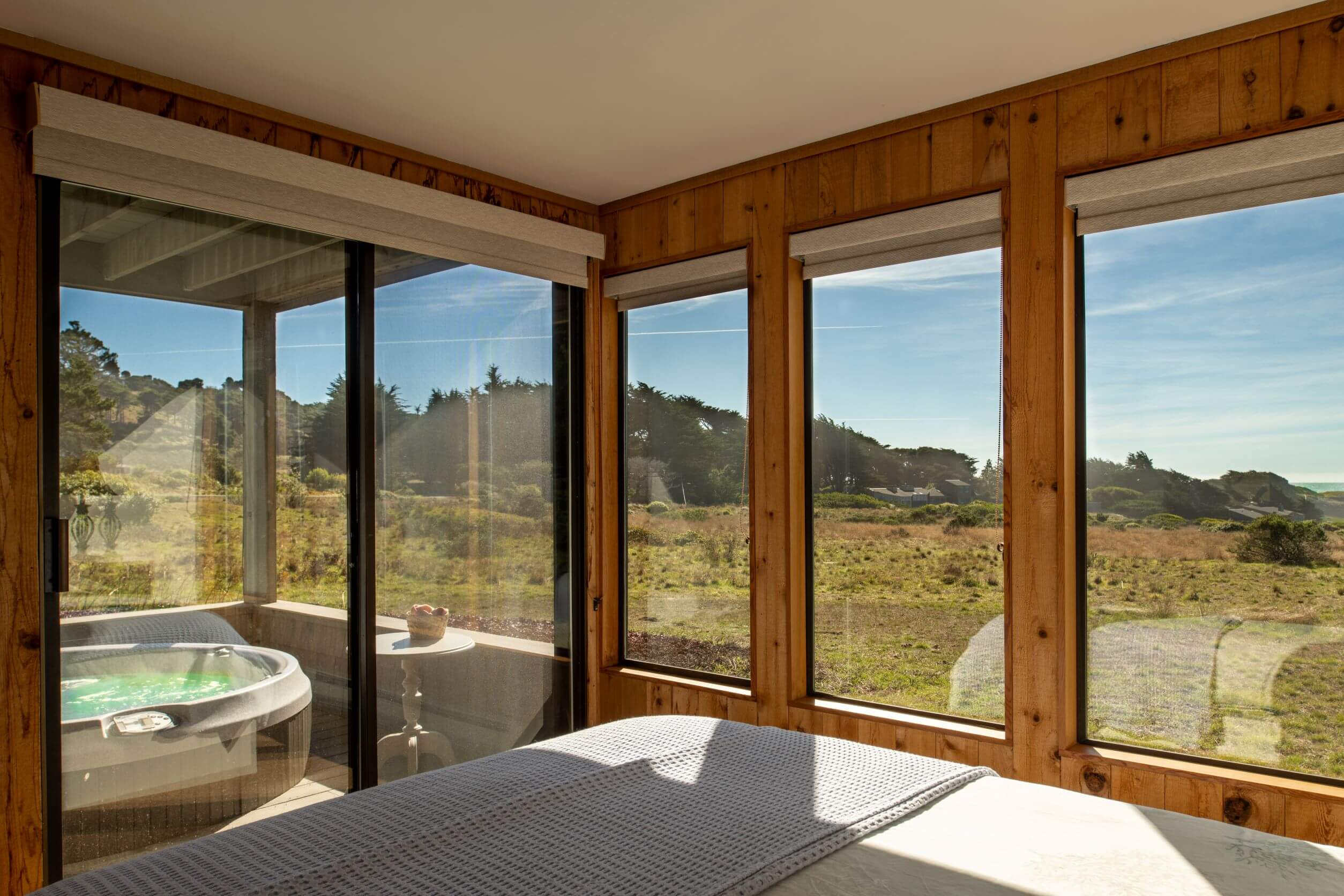 Lighthouse - bright queen bedroom with window view of hot tub and meadow