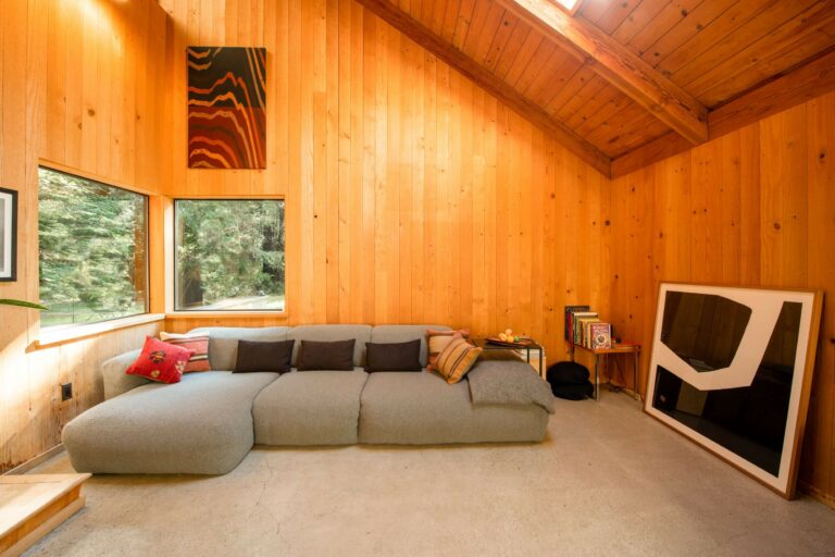 Paradiso - bright spacious living room with large grey sofa and wood walls.
