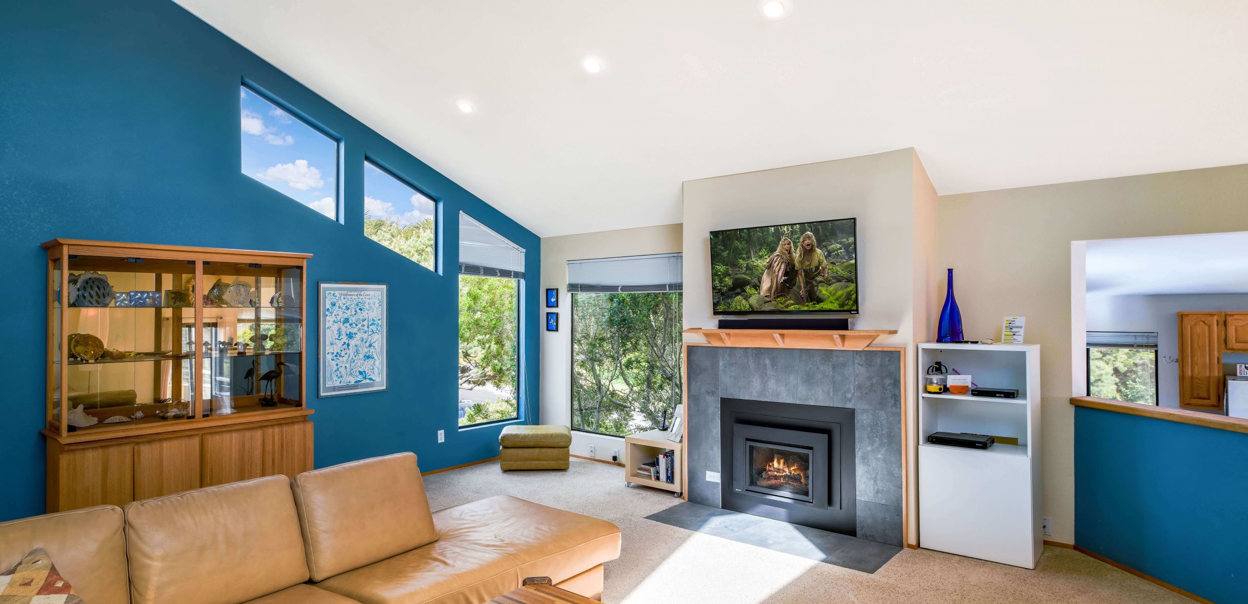 Mare Vista - bright blue walled living room with fireplace and leather couch.