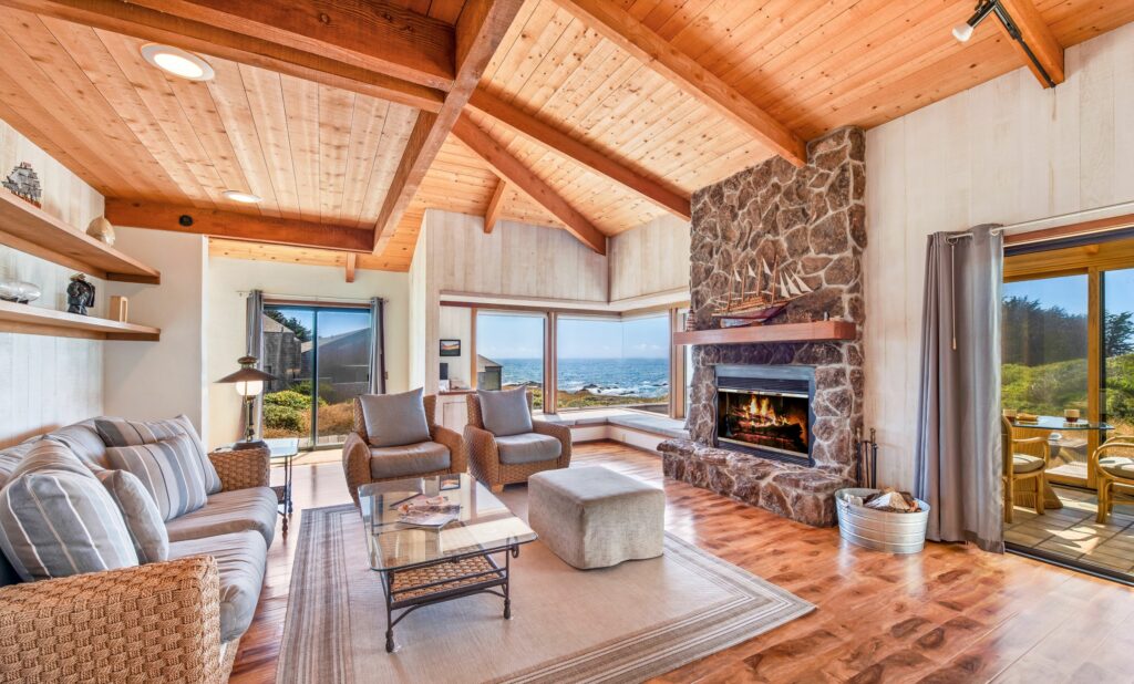 Cove Overlook: living room with wood burning fireplace and wood floors, large windows looking onto cove.
