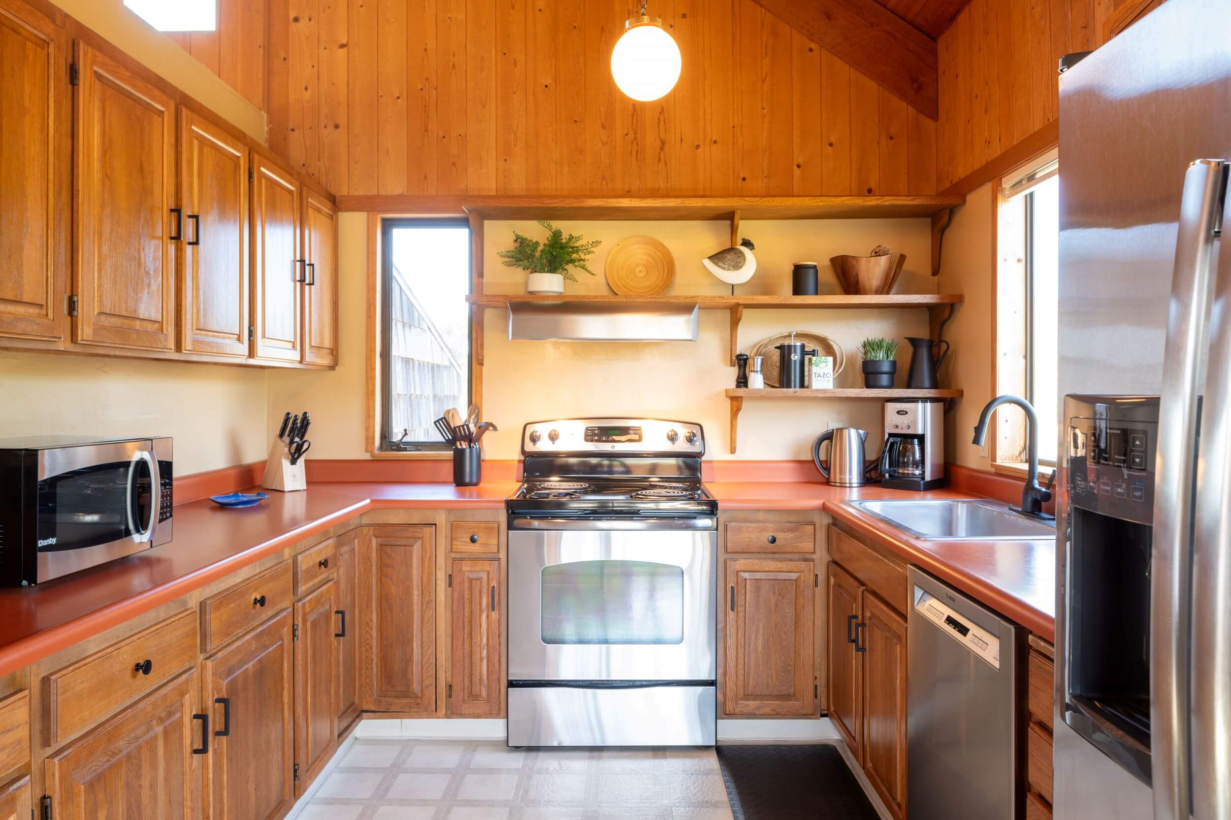 Sea Meadow: bright kitchen with wood walls and cabinets.