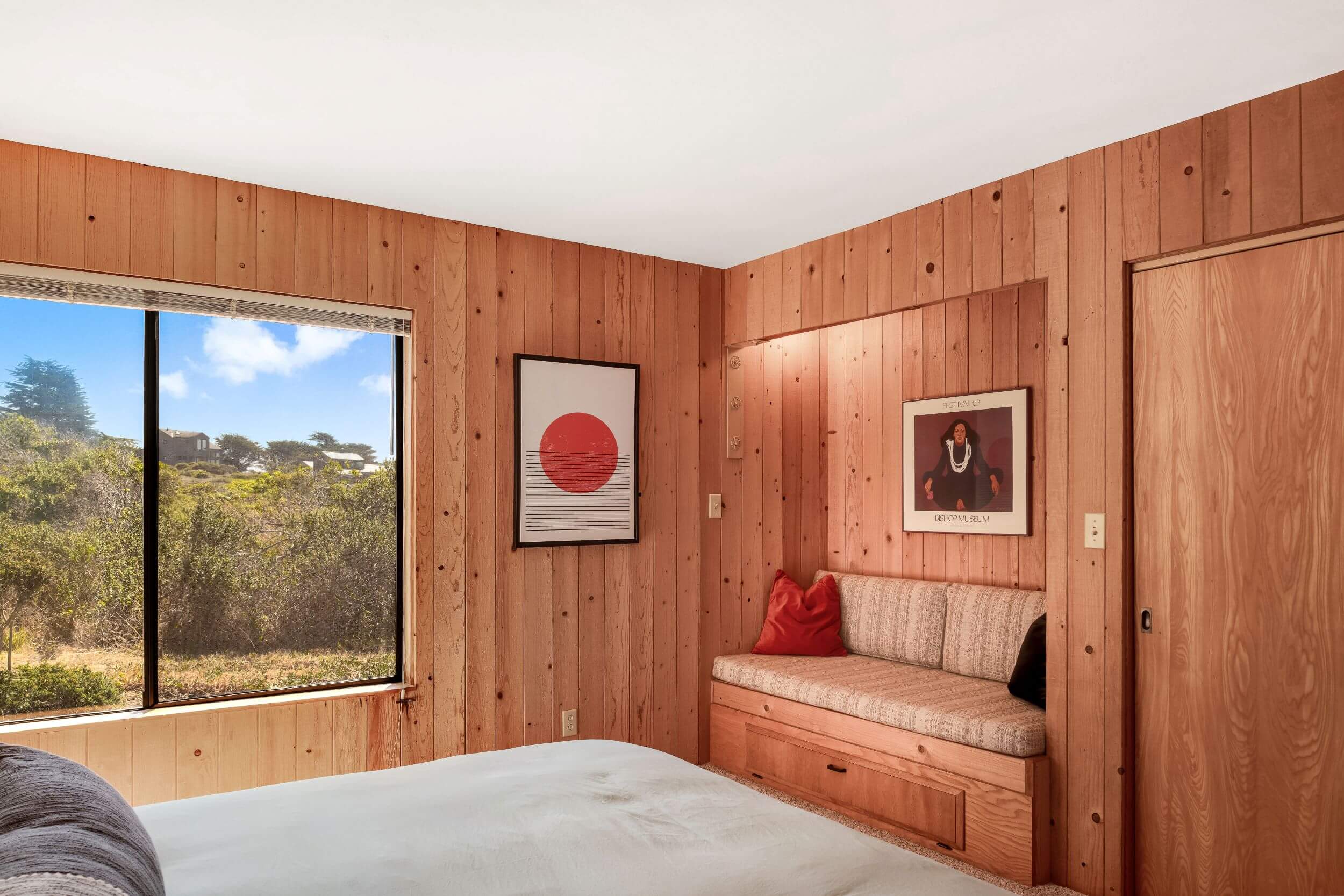 Sea Meadow: 1st large bright bedroom with wood walls, recessed seating and large window looking onto meadow.